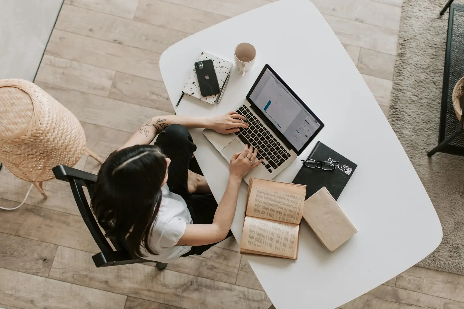 girl using laptop with iphone and books on white table